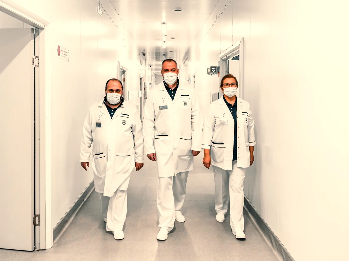Equipe multidisciplinar de saúde caminhando junta em um corredor hospitalar